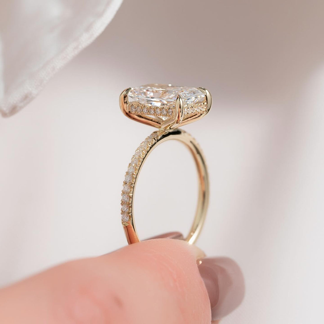 Elongated radiant cut lab grown diamond ring with hidden halo and pave band in yellow gold