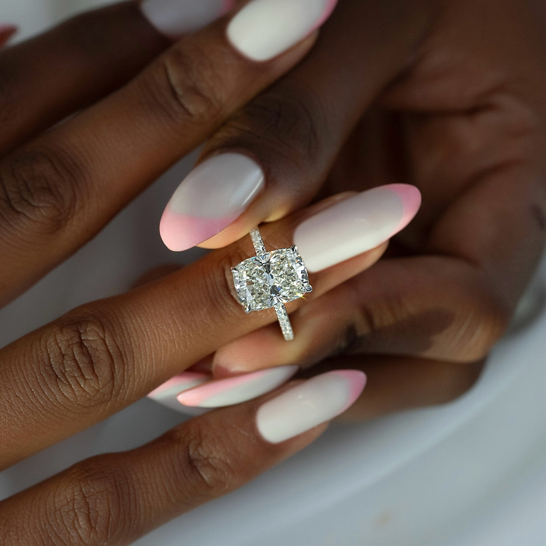 Elongated cushion cut lab grown diamond ring on a fine pave white gold shank worn on the hand