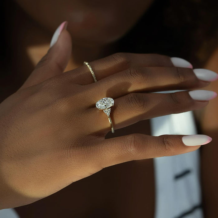 Oval lab grown diamond ring with pear accents on a hand in daylight
