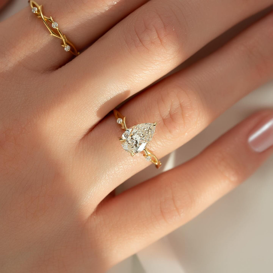 Pear cut lab grown diamond ring on a slender carved twig band in yellow gold worn on the hand