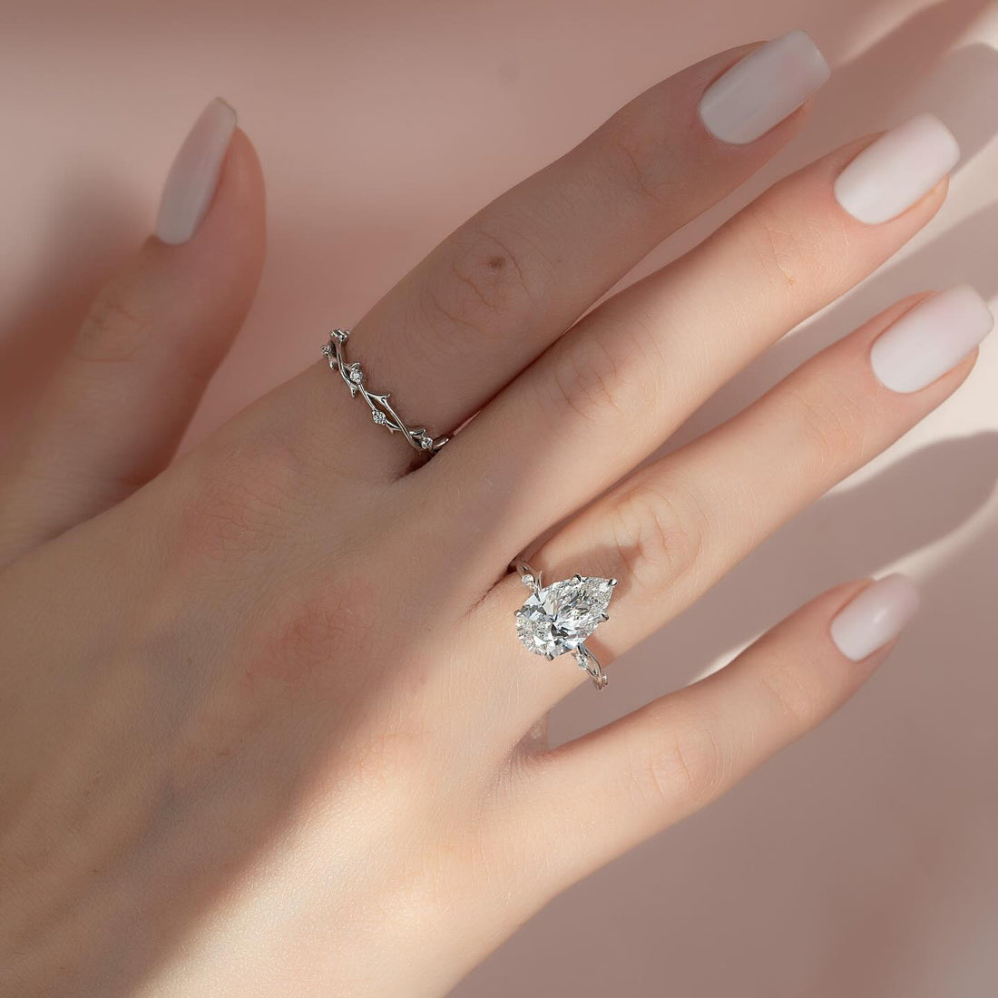 Pear cut lab grown diamond ring with marquise leaf accents in white gold worn on the hand