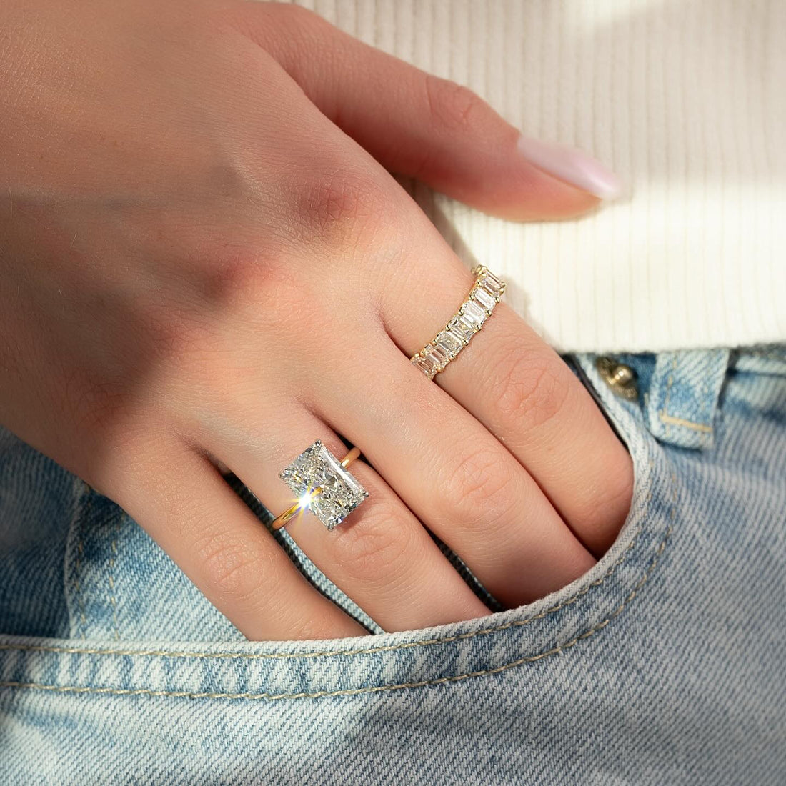 Radiant cut lab grown diamond ring on a wire thin yellow gold band worn on hand
