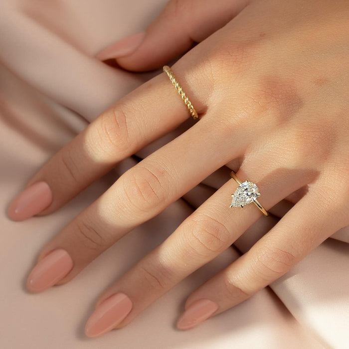 Pear diamond solitaire engagement ring worn on the hand