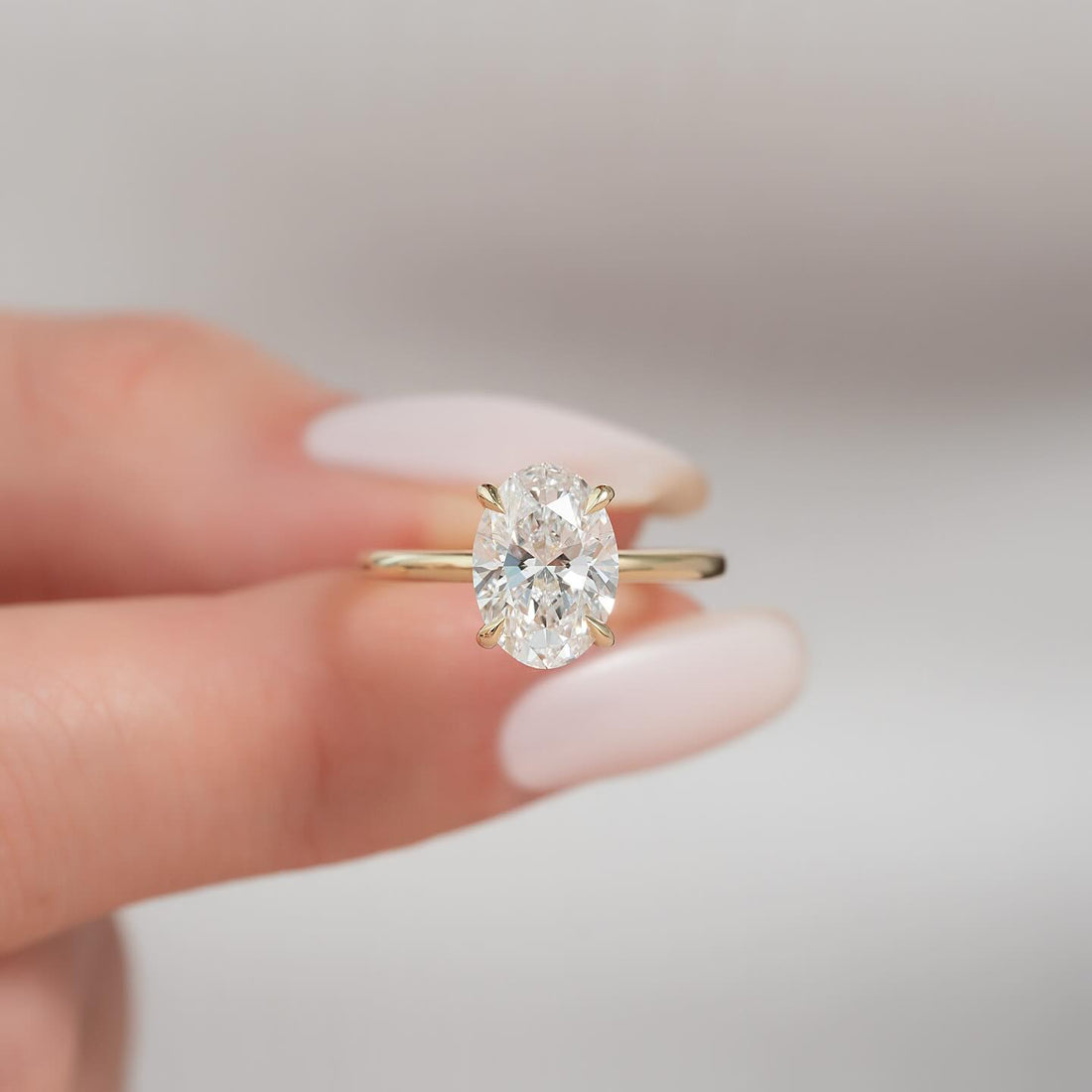 Oval cut lab grown diamond ring with ultra thin yellow gold band and tapered claws