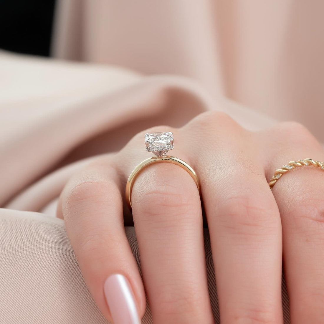 Elongated cushion lab grown diamond ring with hidden halo on a wide plain gold band worn on the hand