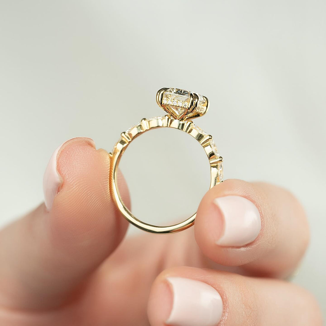 Profile of an elongated cushion cut lab grown diamond ring on a marquise station band in yellow gold