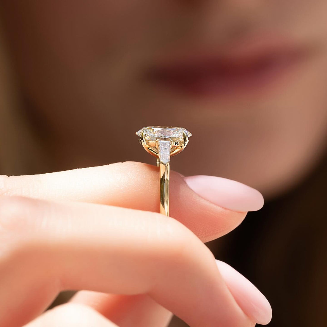 Oval cut lab grown diamond ring with tapered baguette side stones in yellow gold