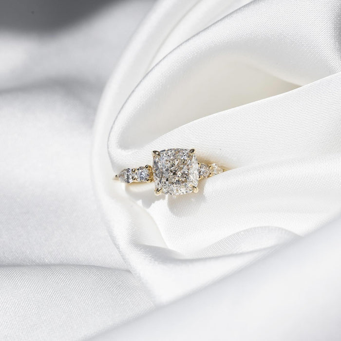 Cushion cut lab grown diamond ring in yellow gold with pear and round shoulder accents
