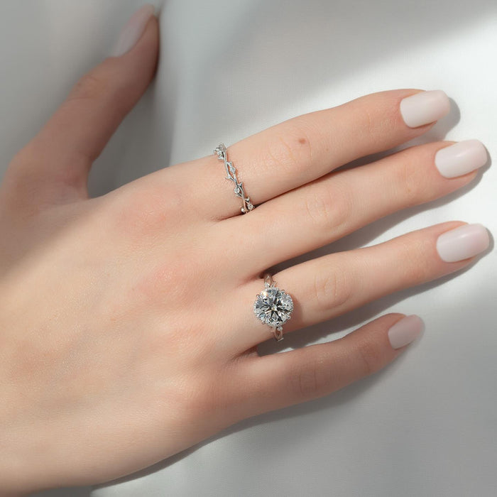 Round cut lab grown diamond halo ring with vine leaf band in white gold worn on the hand