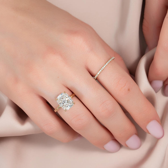 Elongated cushion lab grown diamond solitaire worn on the hand with a pave wedding band