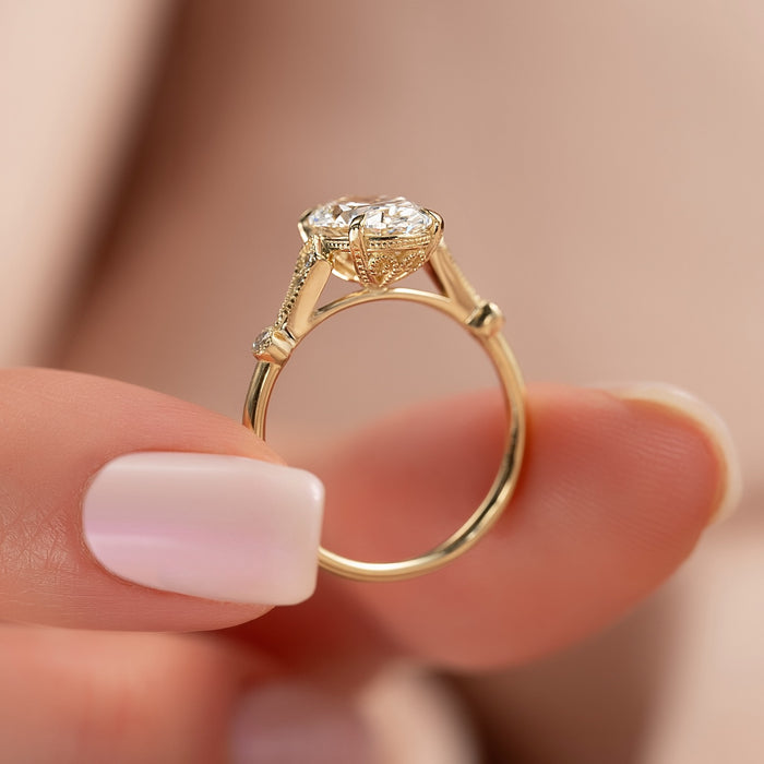 Milgrain detail on the decorated shoulders of the oval diamond ring