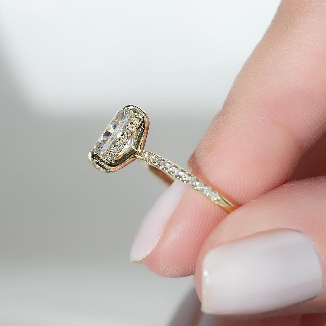 Elongated radiant cut lab grown diamond ring in yellow gold showing the mitred concealed halo