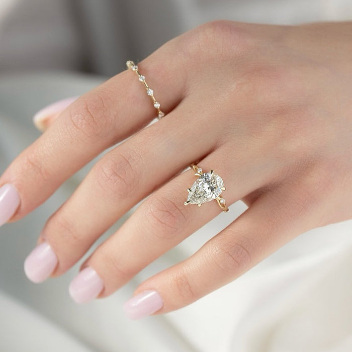 East west pear cut lab grown diamond ring in yellow gold with round accents at each end