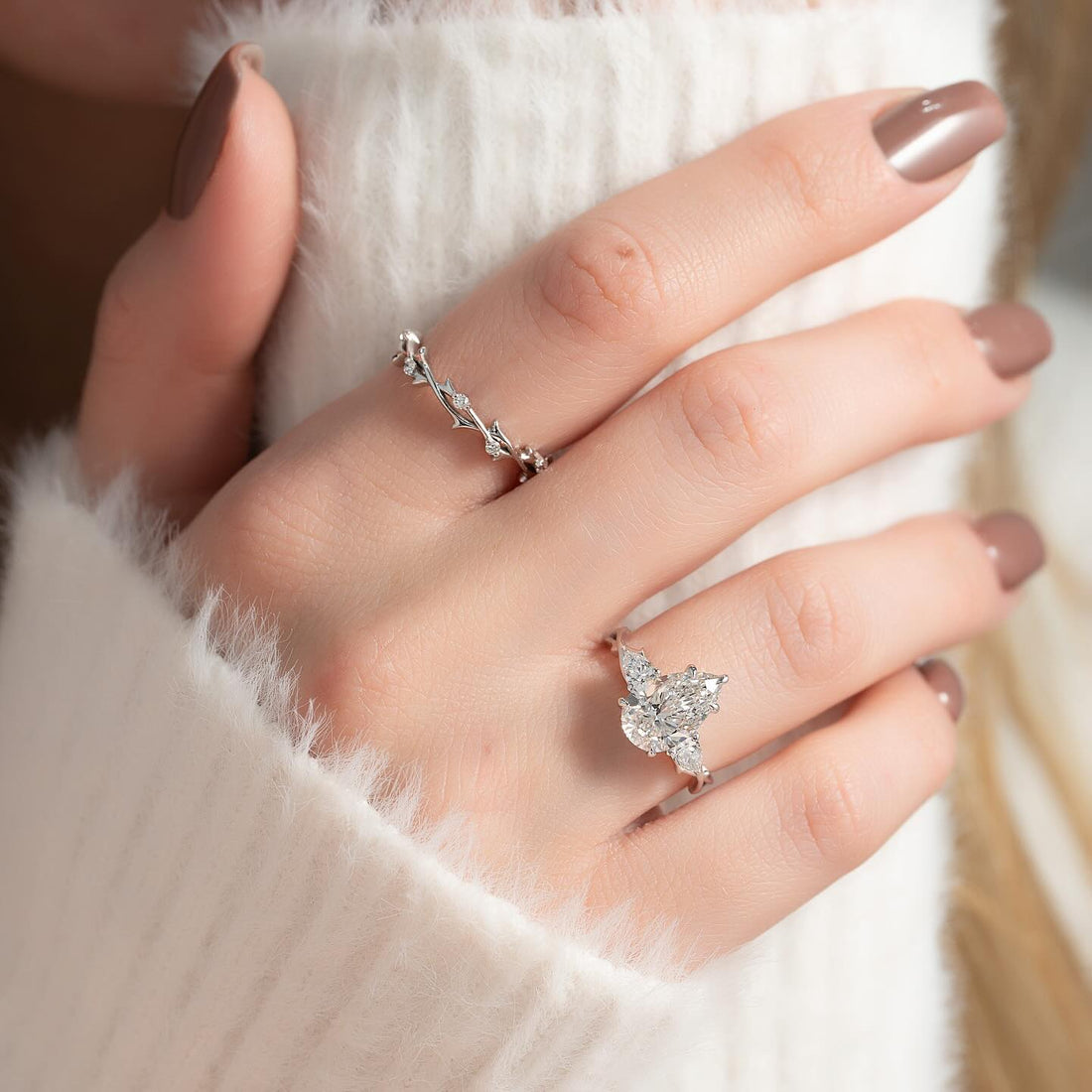 Pear cut lab grown diamond three stone ring with pear side stones in white gold worn on the hand