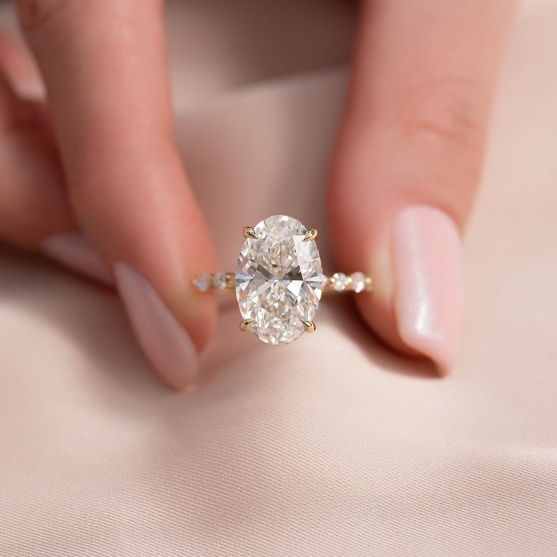 Oval cut lab grown diamond hidden halo ring in yellow gold held in the hand