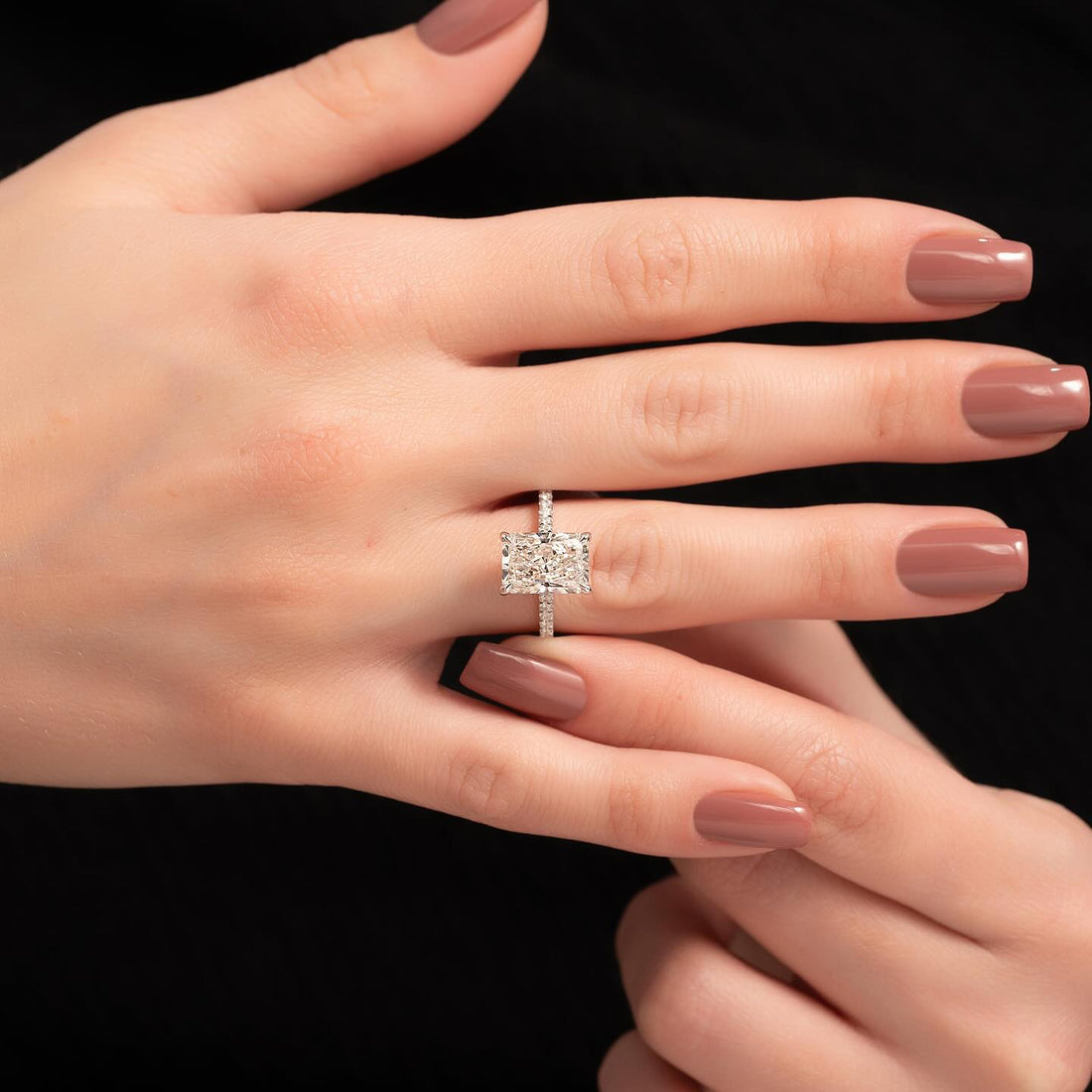 East west radiant cut lab grown diamond ring with pave band in rose gold worn on the hand