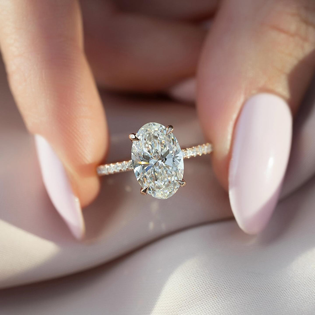 Oval cut lab grown diamond ring on a three quarter pave rose gold band