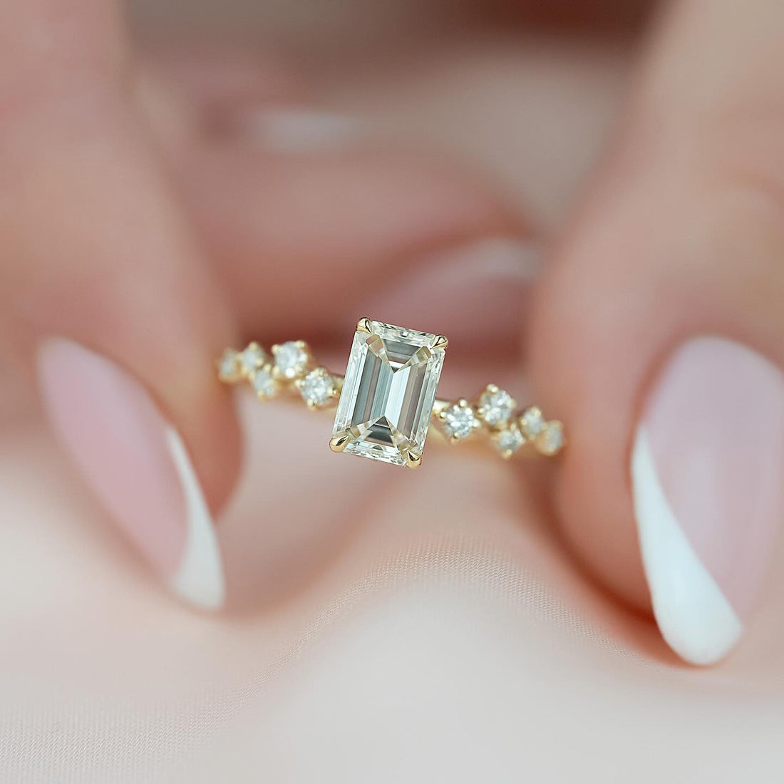 Emerald cut lab grown diamond ring in yellow gold with staggered round accents on a fine band