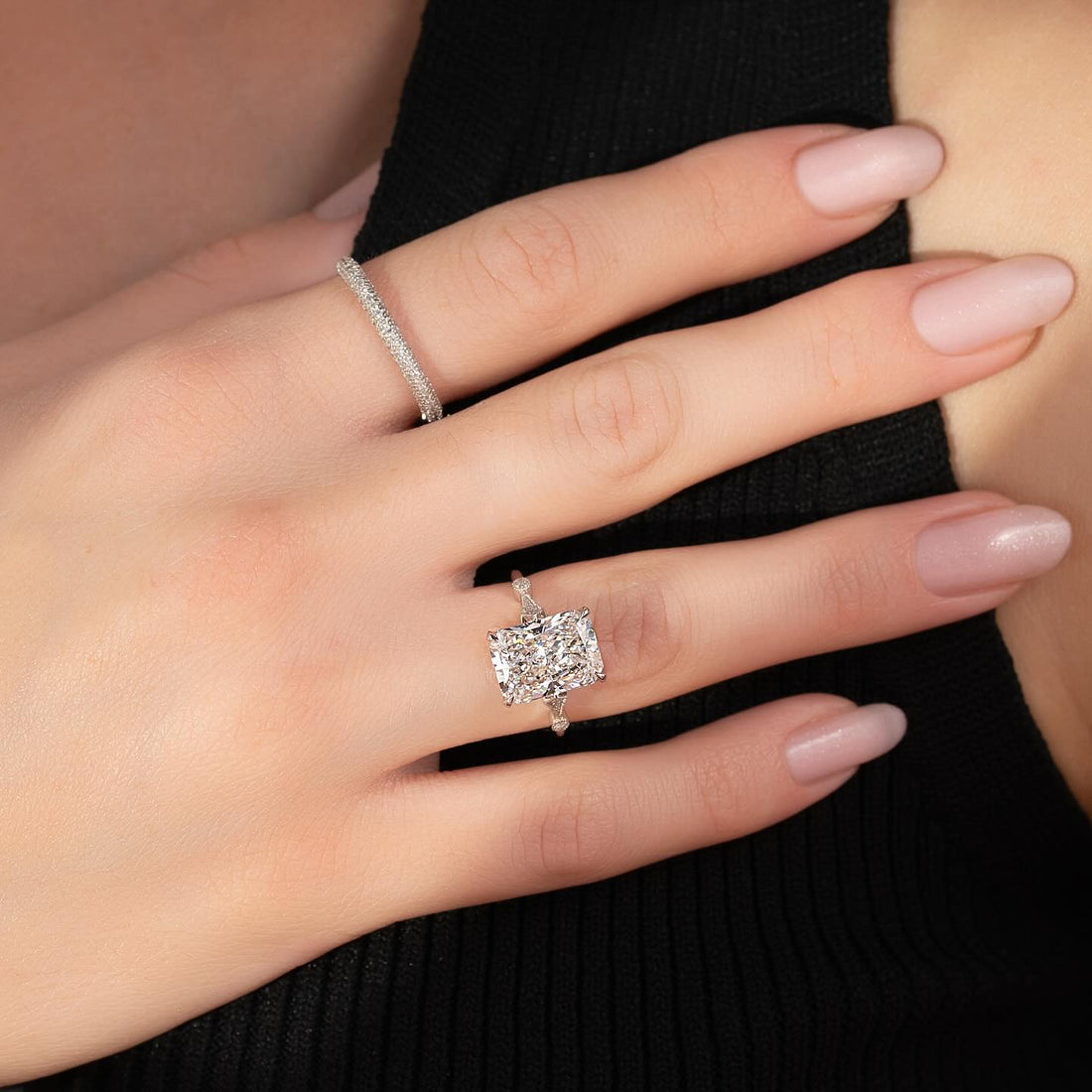 East west radiant cut lab grown diamond ring with fine pave band in white gold worn on the hand