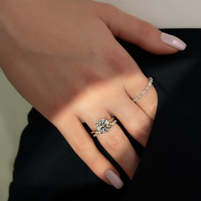 Curved arc of graduated accent diamonds beside the round centre stone