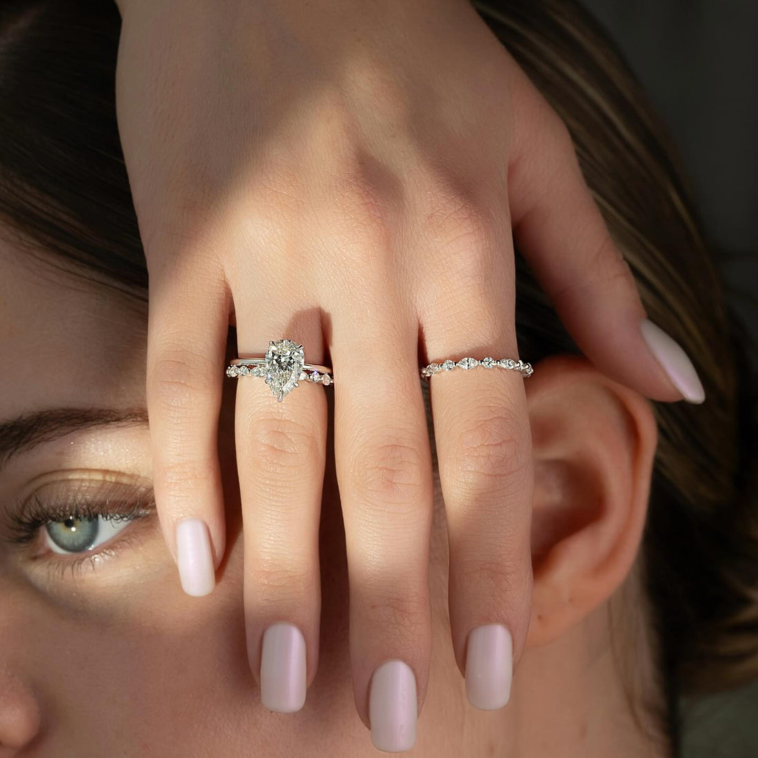 Pear cut lab grown diamond ring with spaced round accent band in white gold