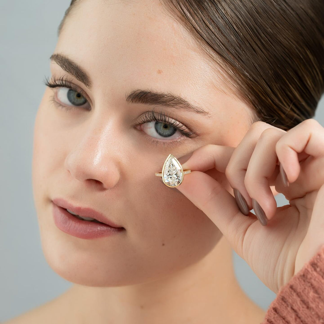 Pear cut lab grown diamond bezel set ring with pave shank in yellow gold