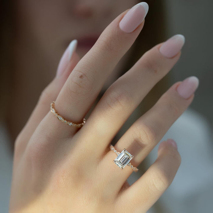 Emerald cut lab grown diamond ring in rose gold on a milgrain scalloped band worn on the hand