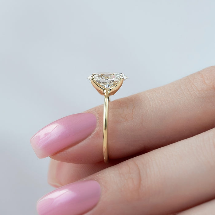Minimal claws holding the oval diamond low against the finger