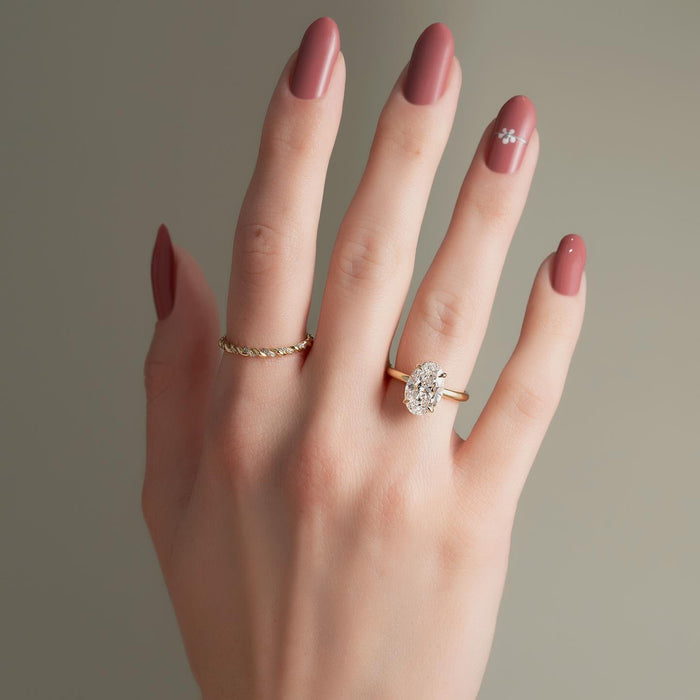 Oval cut lab grown diamond hidden halo ring on a fine yellow gold band