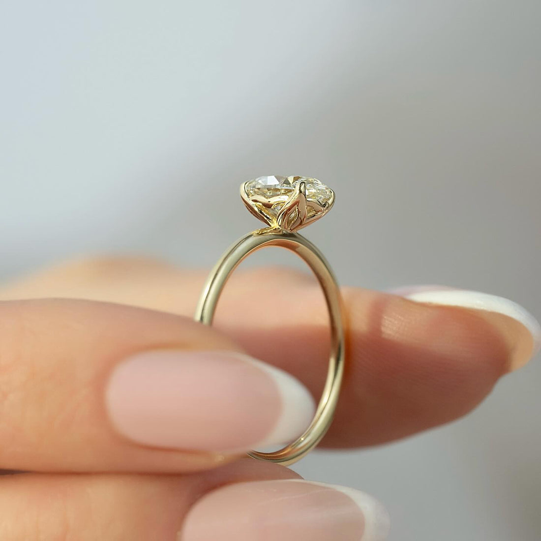 Profile of an oval cut lab grown diamond solitaire ring in yellow gold showing the low set petal basket