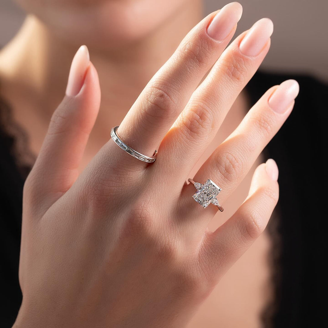 Radiant cut lab grown diamond ring with pear wing accents in white gold worn on the hand