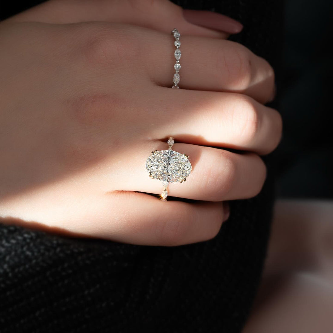 East west oval cut lab grown diamond ring in yellow gold worn on the hand