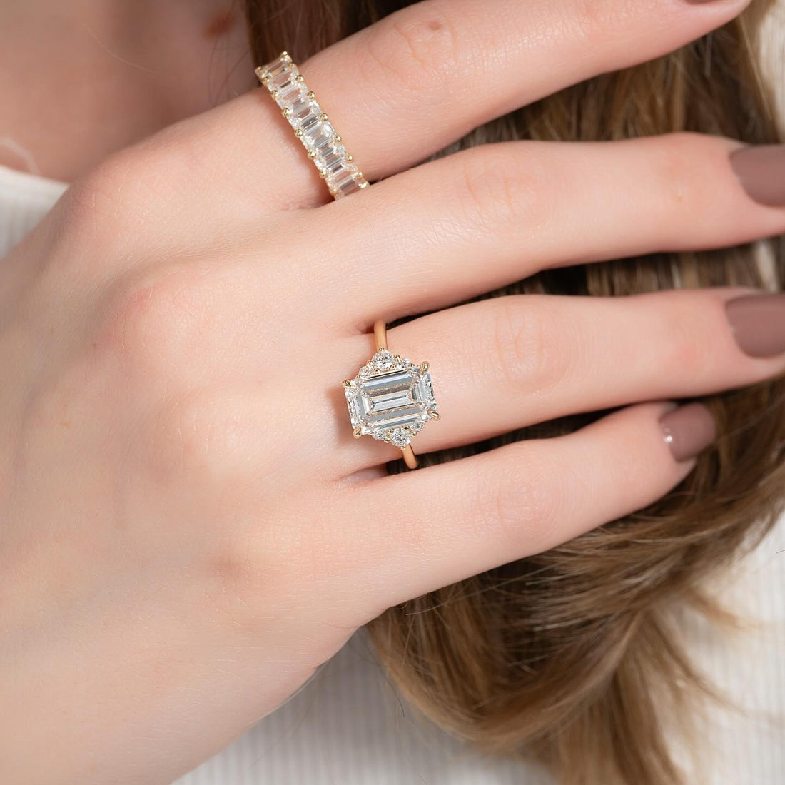Emerald cut lab grown diamond ring with vintage geometric halo in yellow gold worn on the hand
