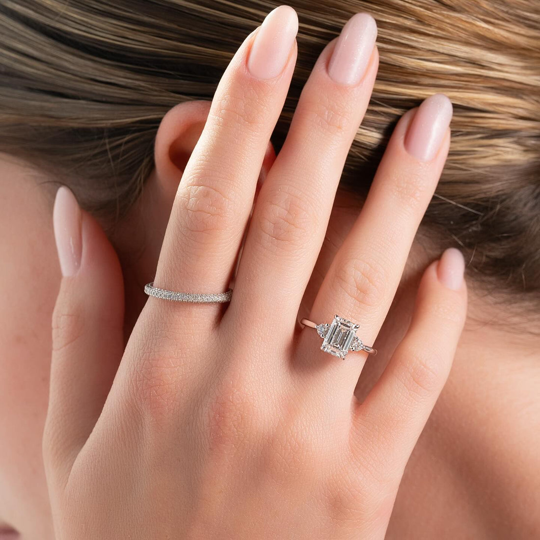 Emerald cut lab grown diamond three stone ring with trapezoid sides in white gold worn on the hand