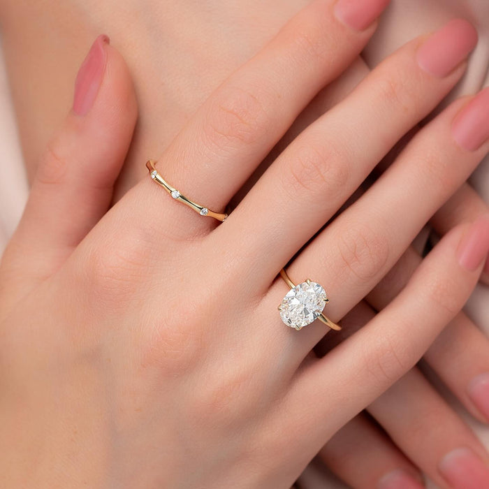 Oval diamond solitaire on a fine gold band worn on the hand