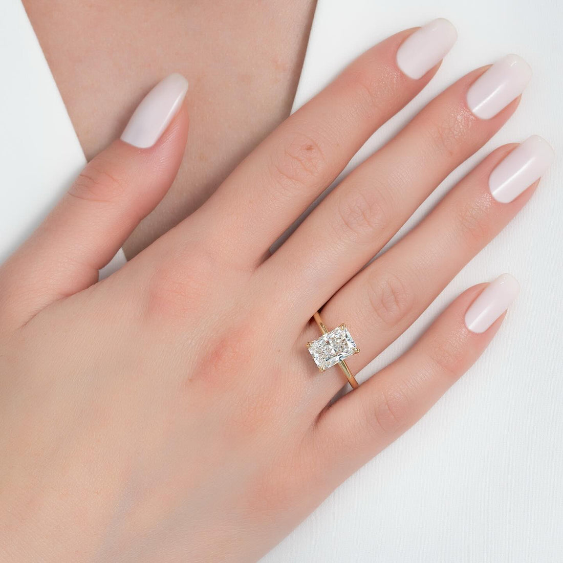 Radiant cut lab grown diamond solitaire on a tapered cathedral yellow gold band