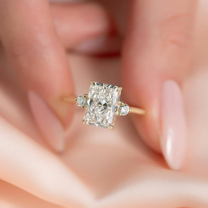 Elongated radiant lab grown diamond ring with round shoulder accents in yellow gold