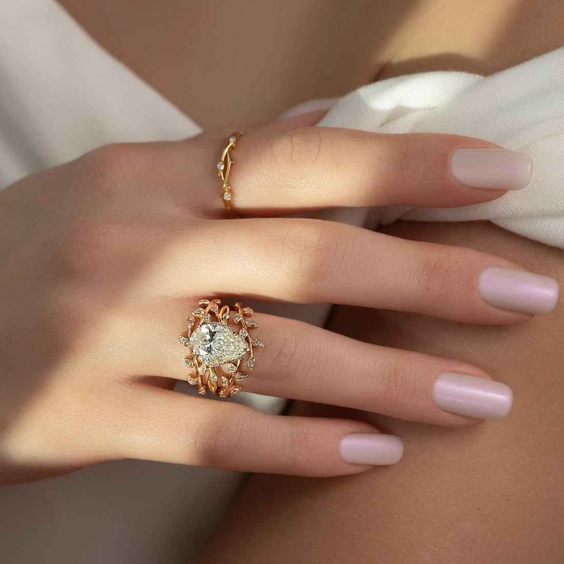 Pear cut lab grown diamond leaf wreath bridal ring set in yellow gold worn on hand