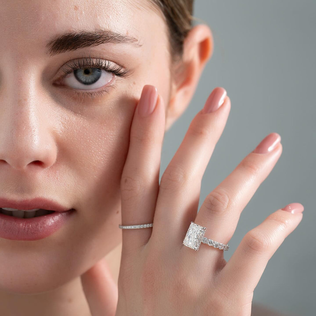 Radiant cut lab grown diamond ring with hidden halo and shared claw diamond band in white gold worn on the hand