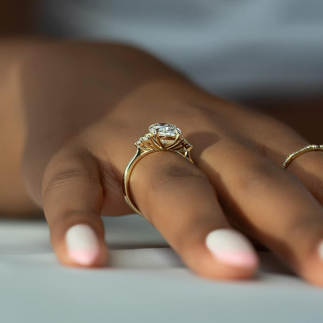Oval cut lab grown diamond ring in yellow gold with fanned pear cluster shoulders worn on the hand