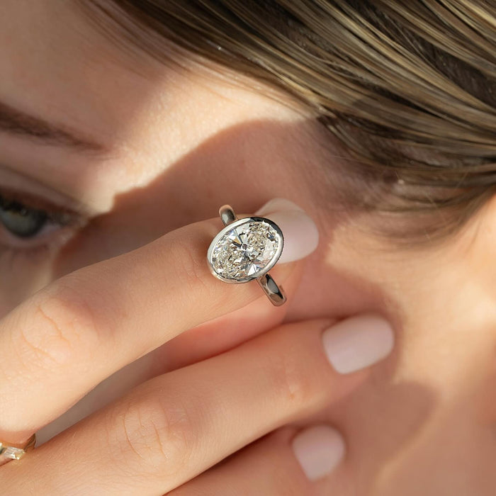 Continuous metal rim enclosing the oval lab grown diamond