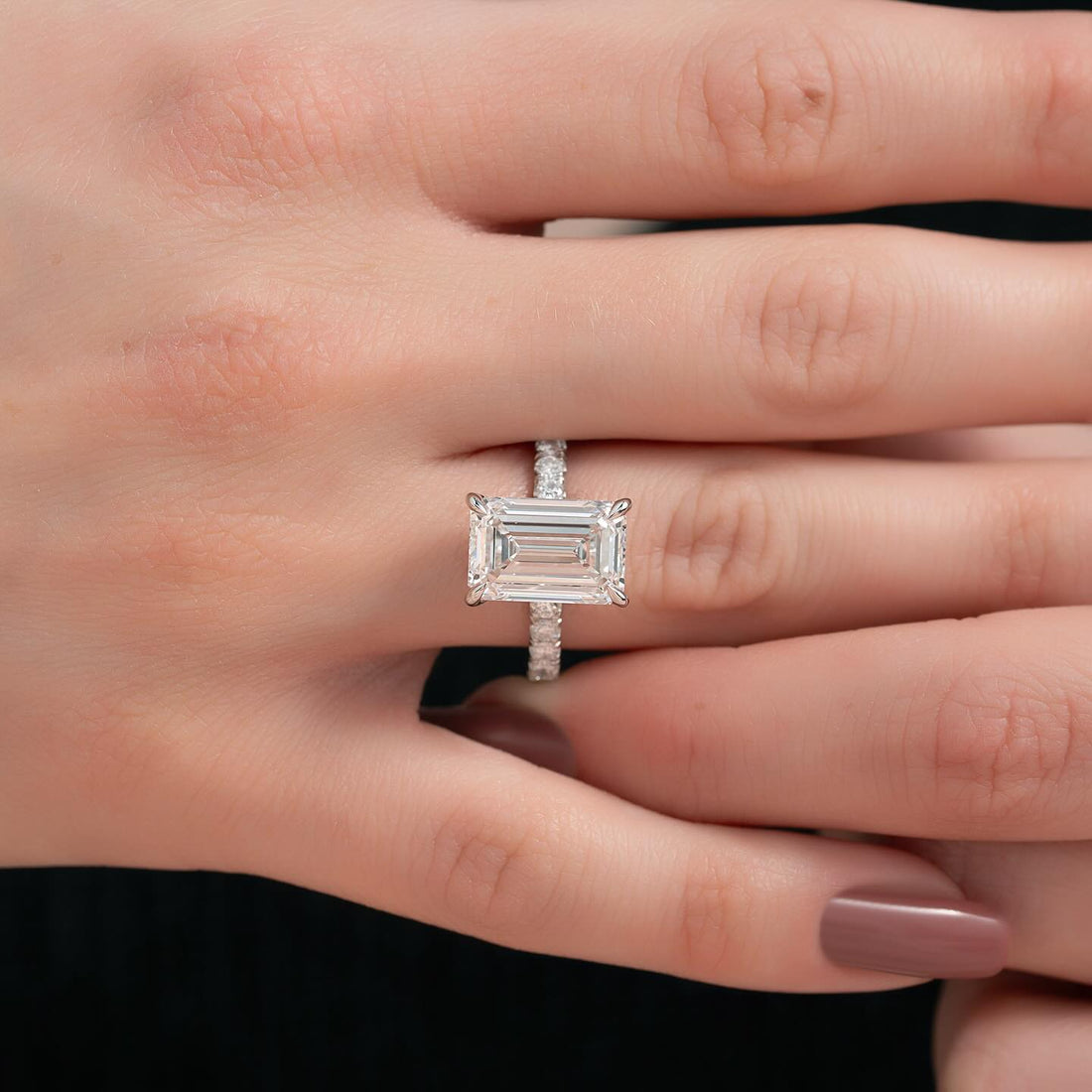 East west emerald cut lab grown diamond ring with micro pave shank in white gold worn on the hand