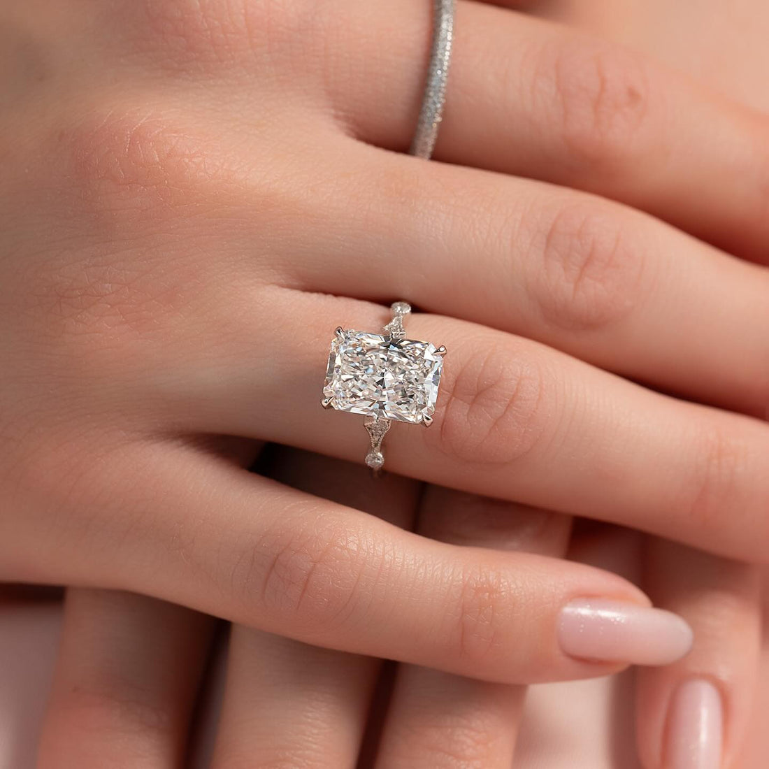 East west radiant lab grown diamond ring with accented wire band in white gold worn on the hand