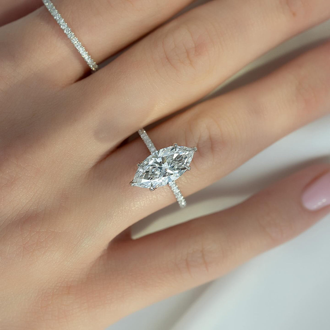 Marquise cut lab grown diamond solitaire ring on a fine pave white gold shank worn on the hand