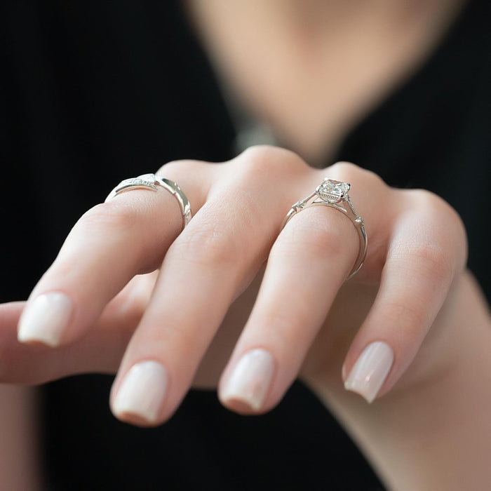 Close view of the pinched waist and milgrain edged shoulder fan beside the emerald cut diamond