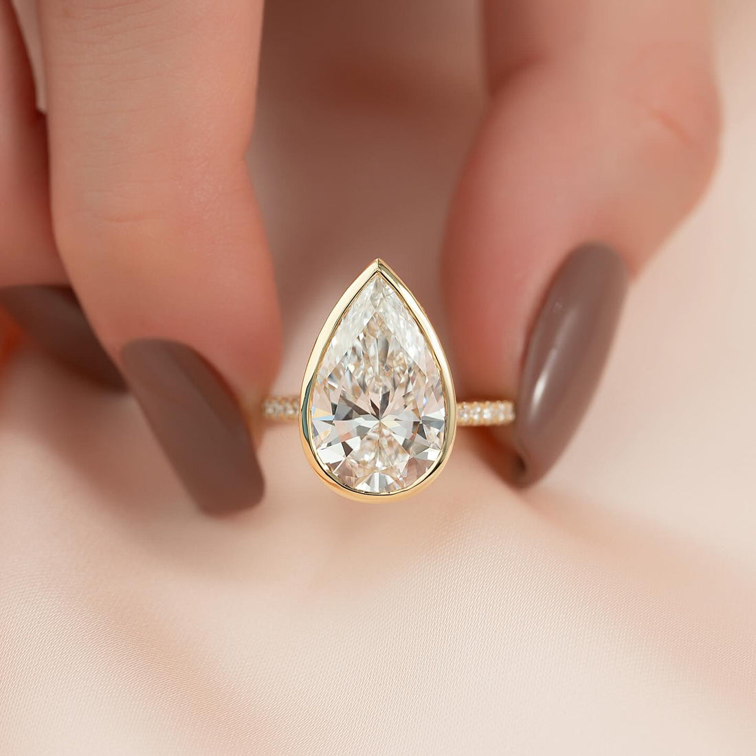 Bezel set pear lab grown diamond solitaire ring with diamond shoulders in yellow gold