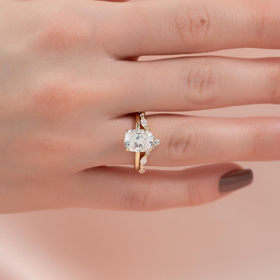 Elongated cushion lab grown diamond ring with marquise and round station band in yellow gold worn on the hand