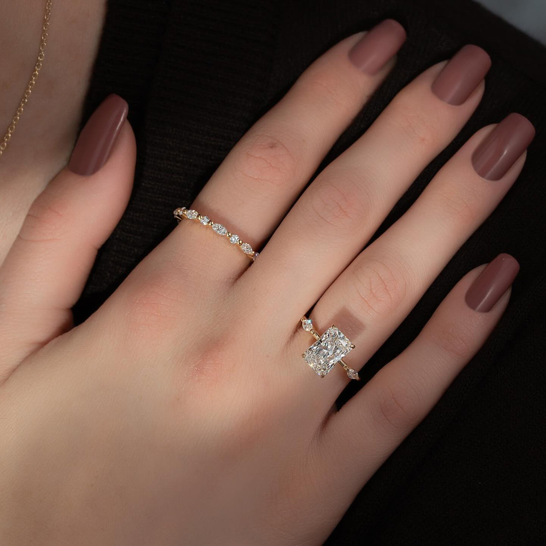 Elongated radiant cut lab grown diamond ring on a slim accent band in yellow gold worn on the hand