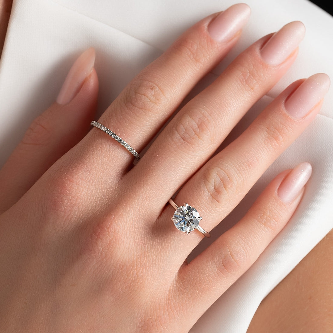 Round brilliant lab grown diamond solitaire ring on a thin plain white gold band worn on the hand