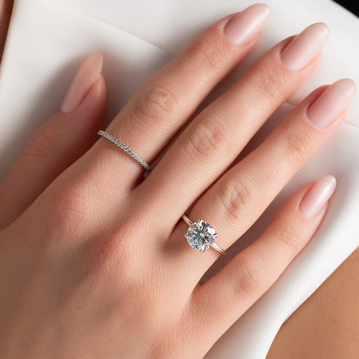 Round brilliant lab grown diamond solitaire ring on a thin plain white gold band worn on the hand